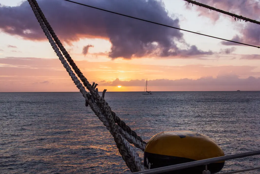 Sonnenuntergang in der Karibik mit einem Segelboot im Hintergrund